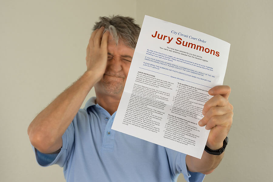 Frustrated man holds up a summons to jury duty in NYC.