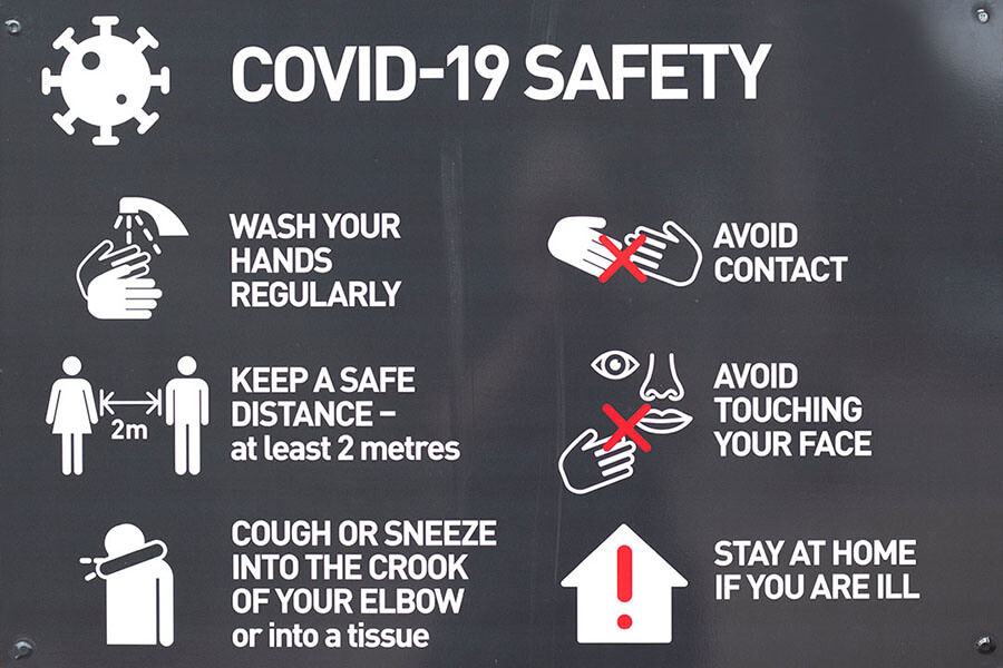 Photo of a blackboard with COVID-19 workplace safety precautions to wash hands, keep a safe distance, avoid contact, and stay home when ill.