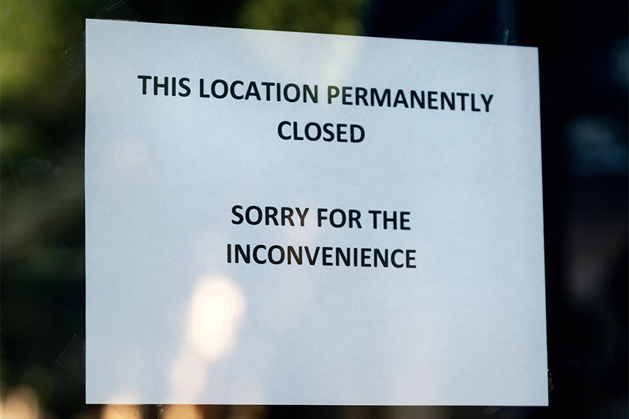 A sign hangs on a dark doorway letting people know that the business within has closed permanently.