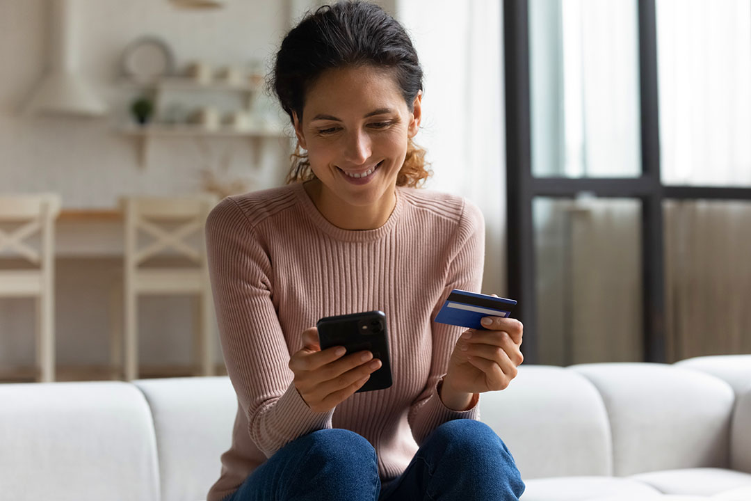 Photo of a woman worker holding a smartphone and a payroll paycard supplied by her small business employer in New York State.