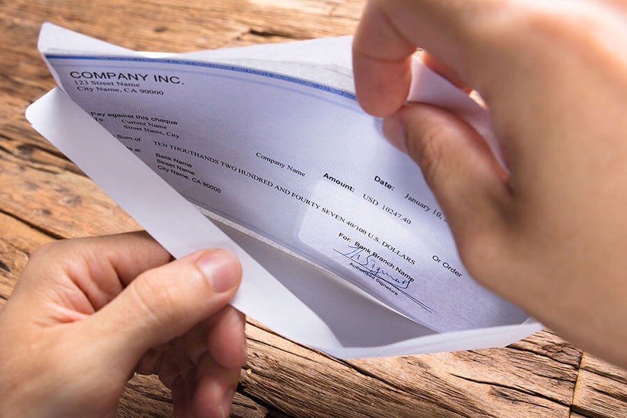 Photo of a paycheck in an envelope showing how payroll printback checks help employers accommodate employee needs and save money.